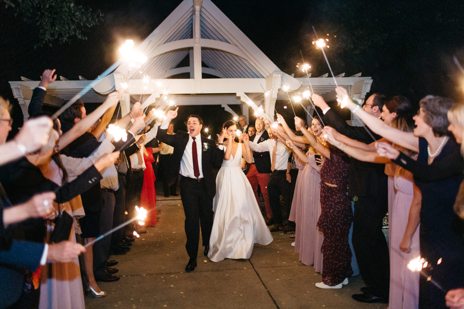 This photo shows the grand exit of the bride and groom at their wedding at Bearpath Golf and Country Club. The couple and their guests participated in a magical sparklers parade. This final touch added a sparkling and enchanting moment to their already perfect day, making it a night to remember.