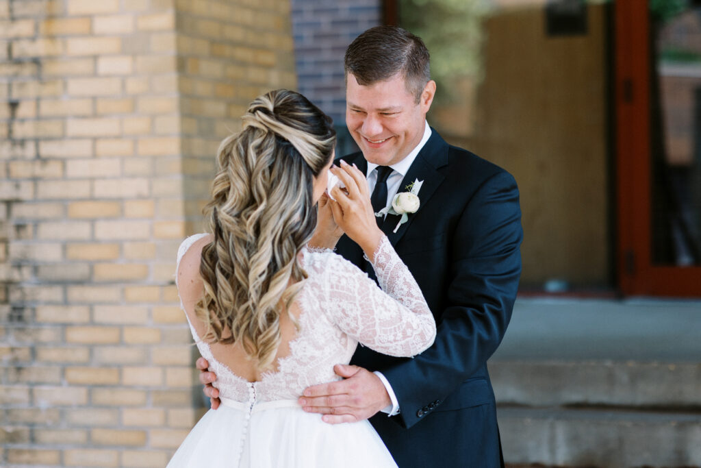 The groom sees his bride for the first time, speechless, while she wipes away joyful tears. This image illustrates an emotional first look, a wonderful moment that deserves to be remembered forever. Captured by Toly Dzyuba Photography.