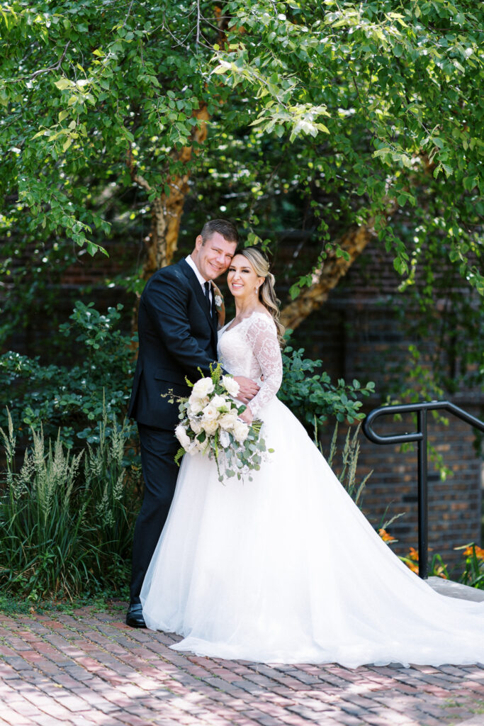 The groom and bride are posing in front of the Minneapolis skyline. They are smiling, looking at the camera.