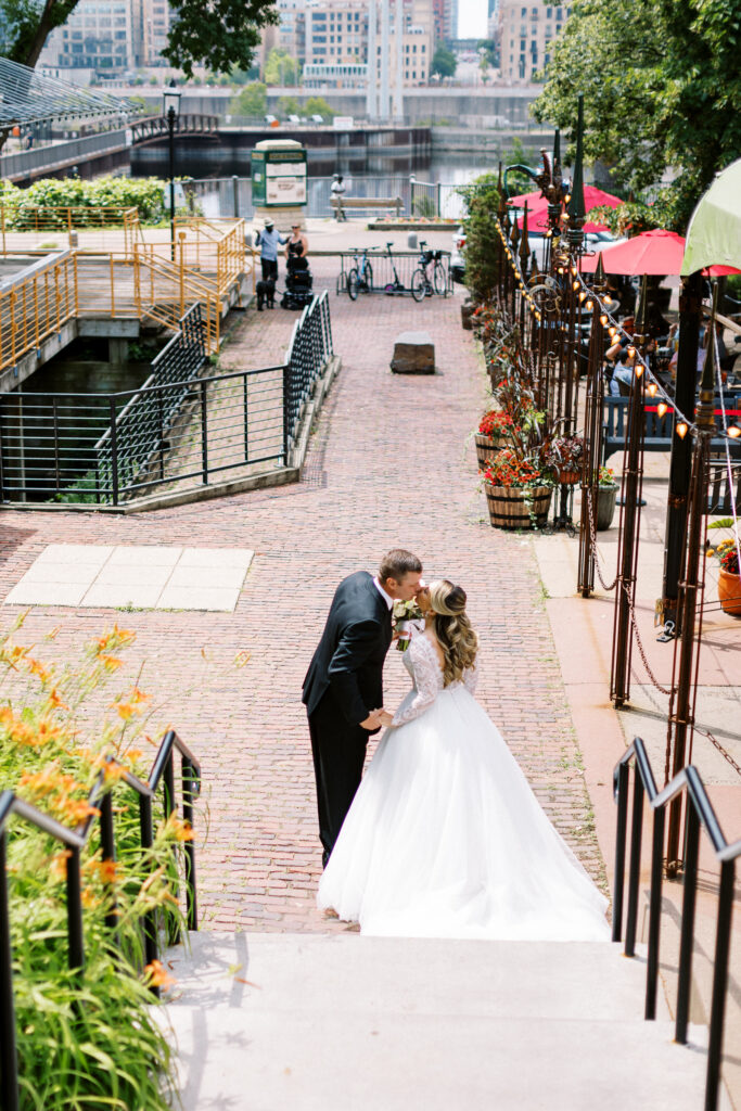 A bride and groom share a tender kiss, with the Minneapolis skyline in the background.