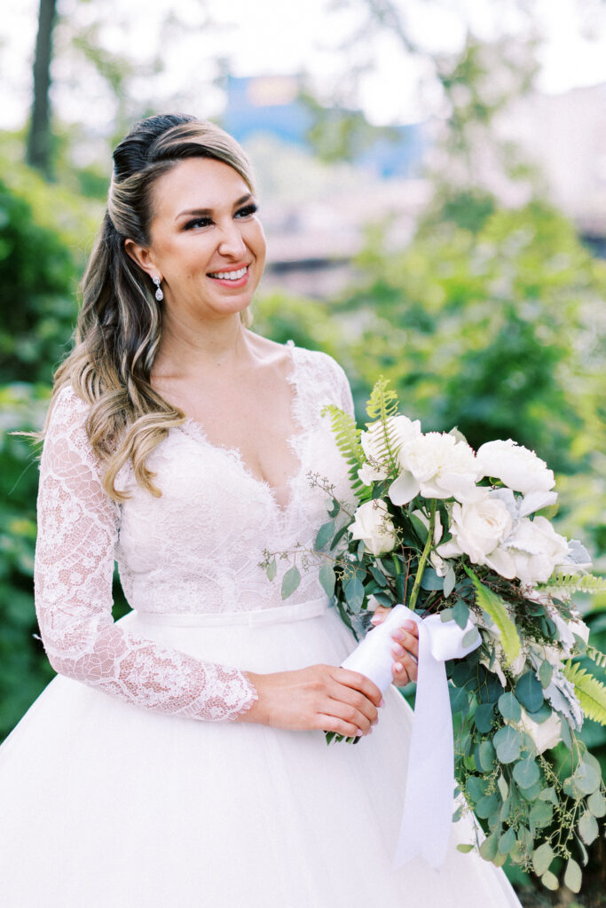 A bride with a smile holds her bridal bouquet in Minneapolis, MN. Aster Cafe wedding venue.