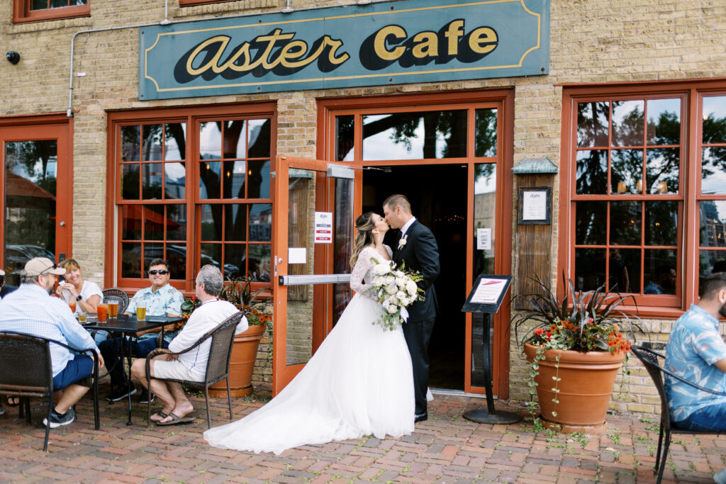 Groom and bride kissing at the front entrance of Aster Cafe in Minneapolis. 