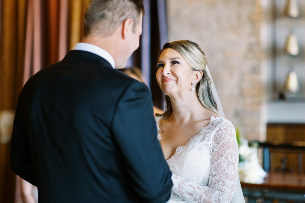 Bride at wedding ceremony. Tears on her face. Looking at groom.
