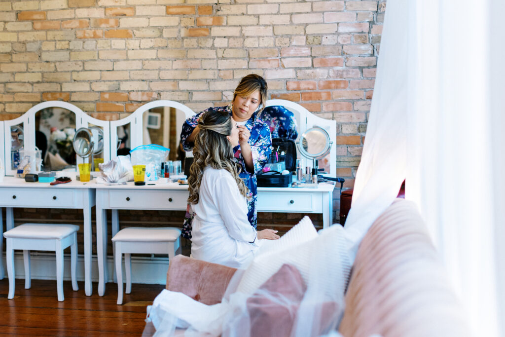 The bride is getting her makeup done on her wedding day at Aster Weddings & Events wedding