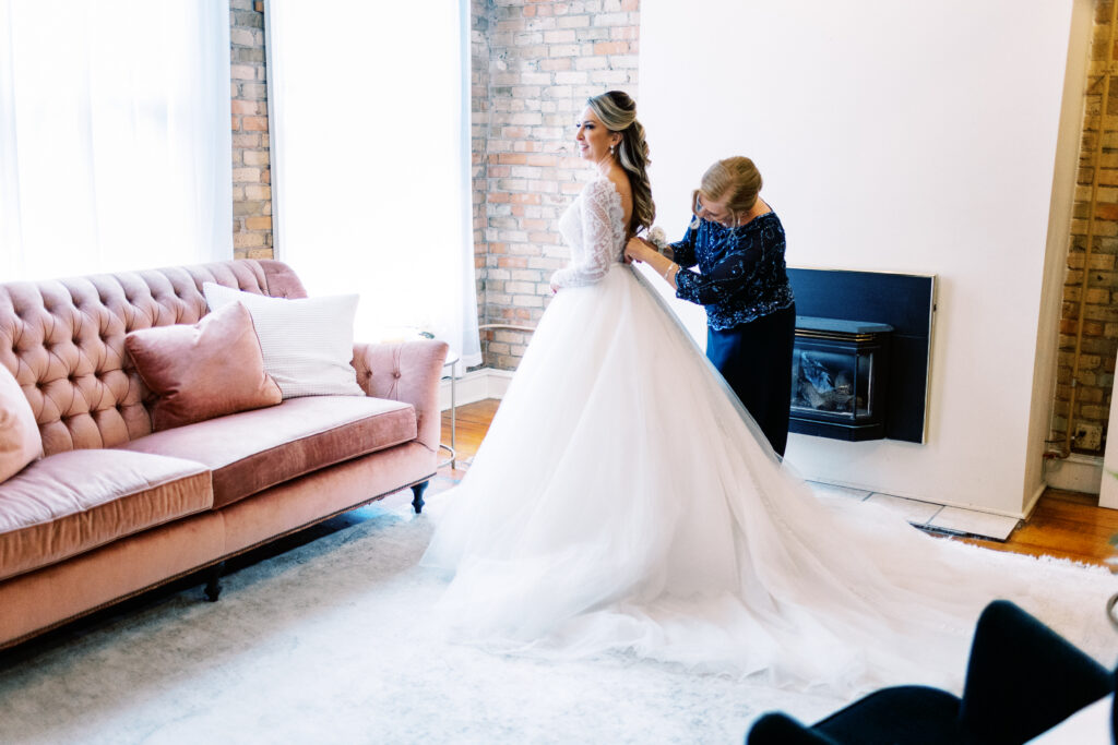 Minneapolis wedding photographer capturing the moment of the mother helping her daughter with the dress.