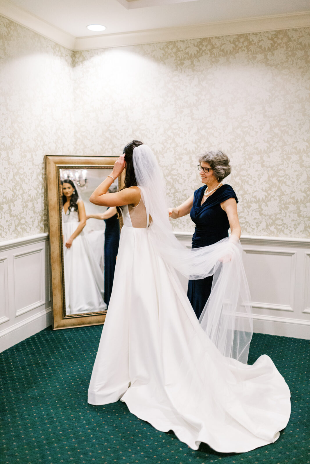 Mom helps the bride get ready for her big day at Bearpath Golf & Country Club. The mom lovingly smoothes out the bride's wedding gown.