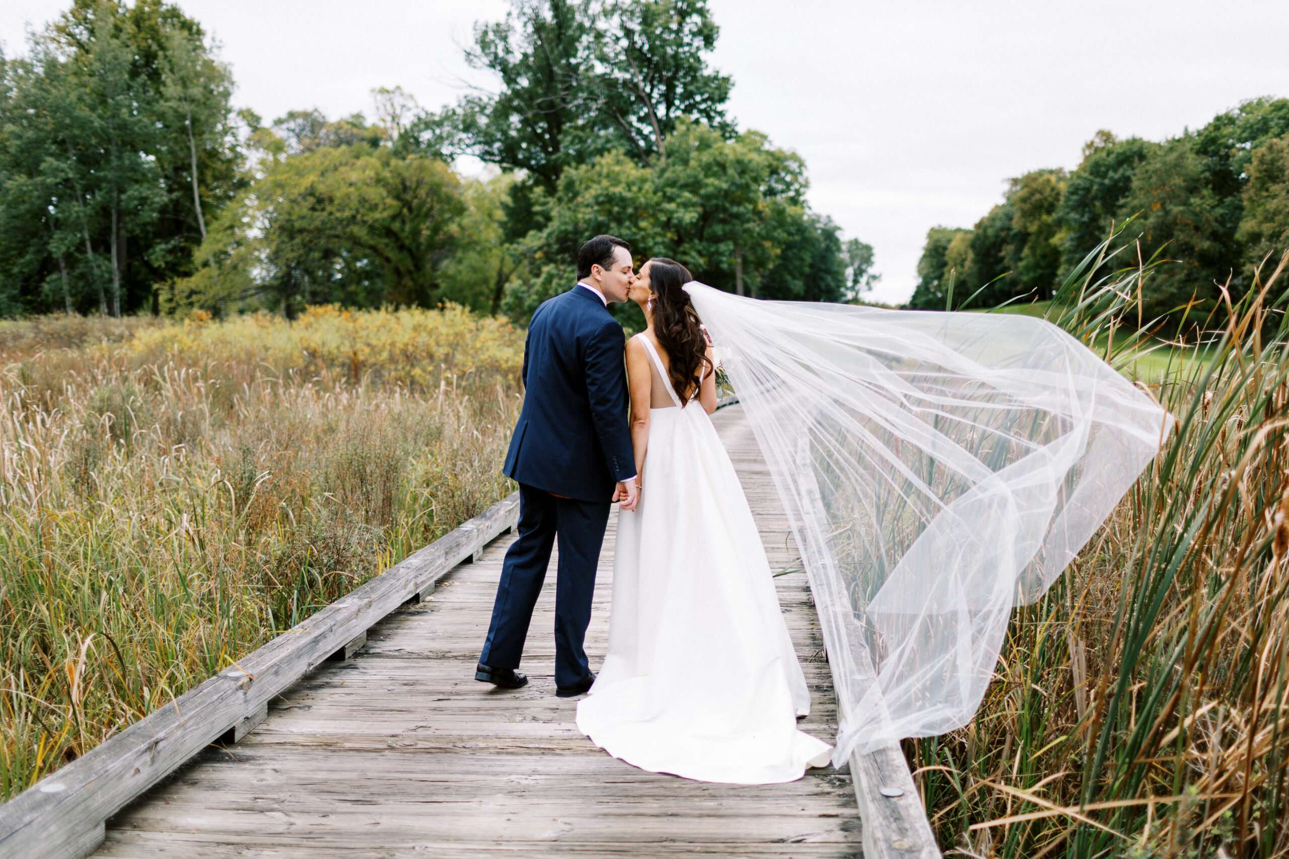 Newlyweds kissing on the boardwalk at Bearpath Golf & Country Club after their ceremony.