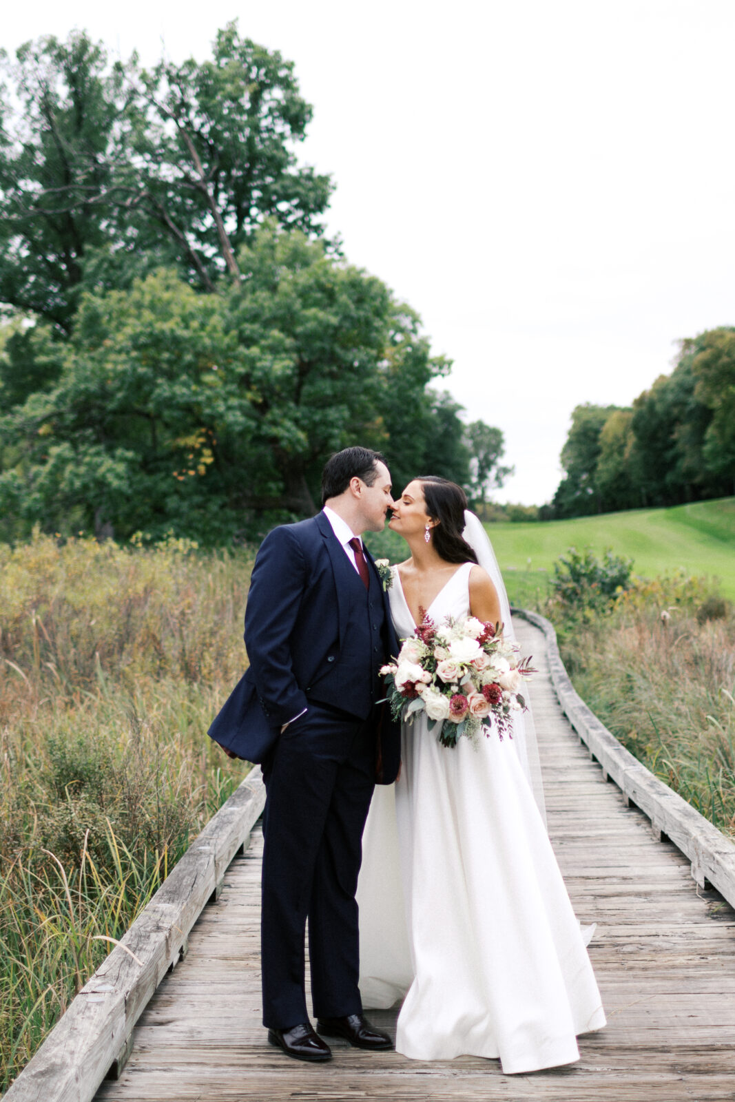 Bride and groom kissing on a boardwalk. 