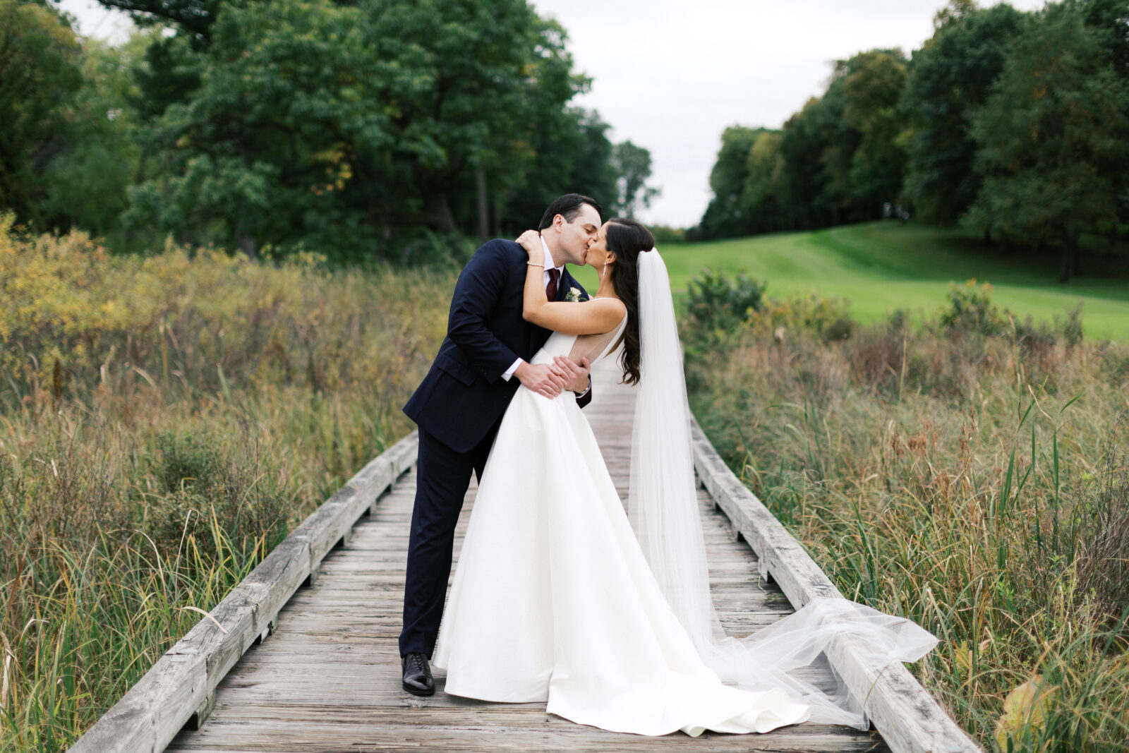 Bride and groom kissing on a boardwalk. 