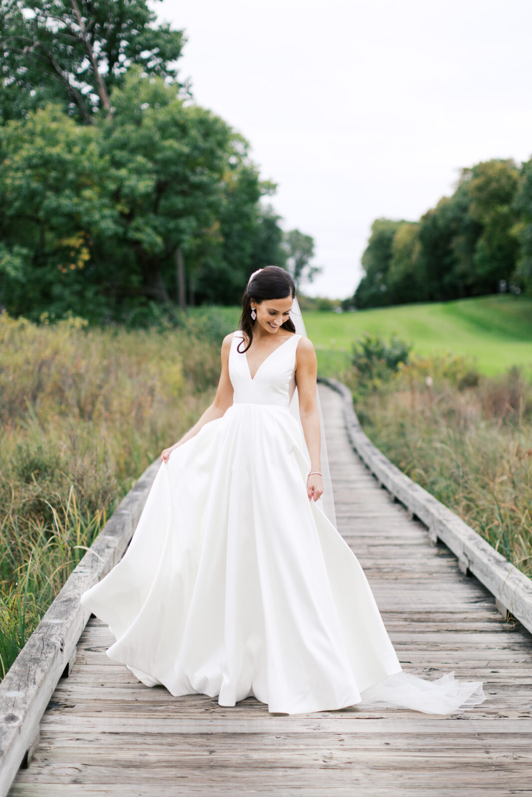 Bride is showing of her beautiful wedding dress on a boardwalk at Bearpath Golf & Country Club. 