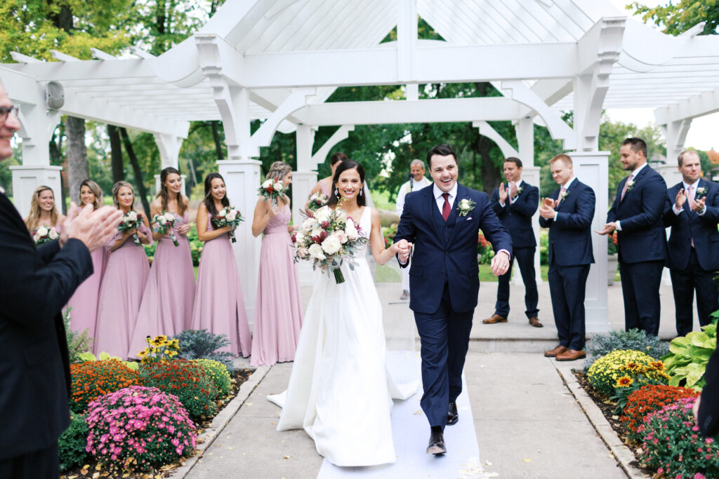 A newly married couple makes a grand exit down the aisle at Bearpath Golf & Country Club. They look so happy and joyful walking holding hands.