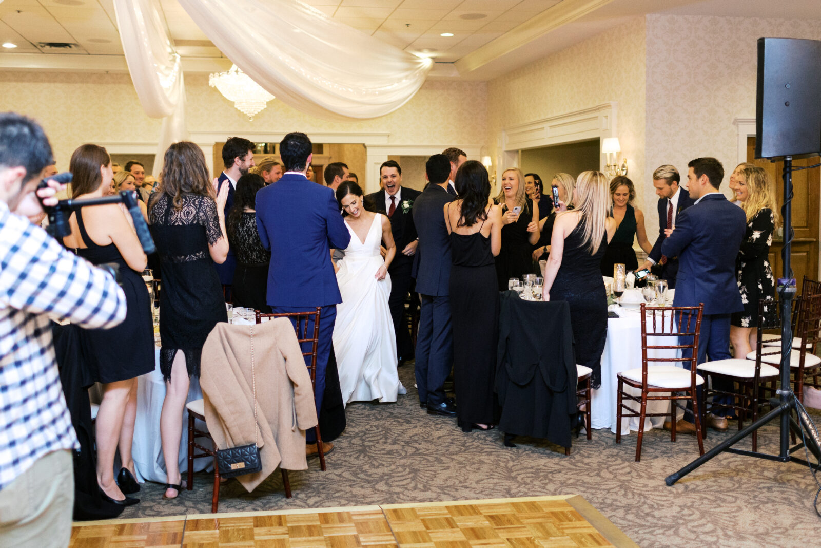 Bride and groom doing a grand entrance through the crowd with folks cheering at Bearpath Golf and Country Club in Eden Prairie 