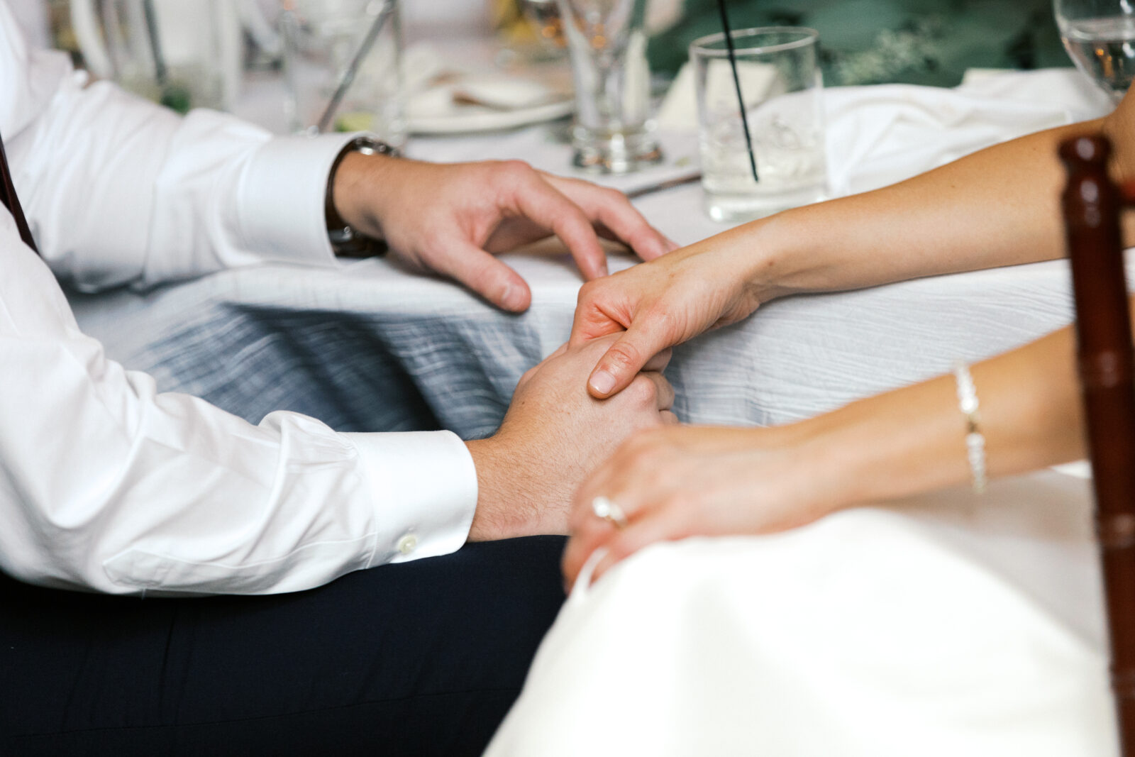 Bride and groom holding hands at the reception.