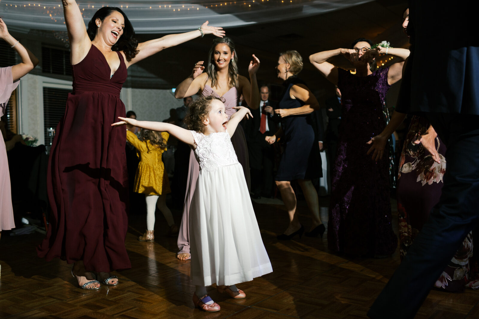 The flower girl is dancing on the dance floor at the wedding. She is wearing a white dress and looks adorable. Eden Prairie wedding. 