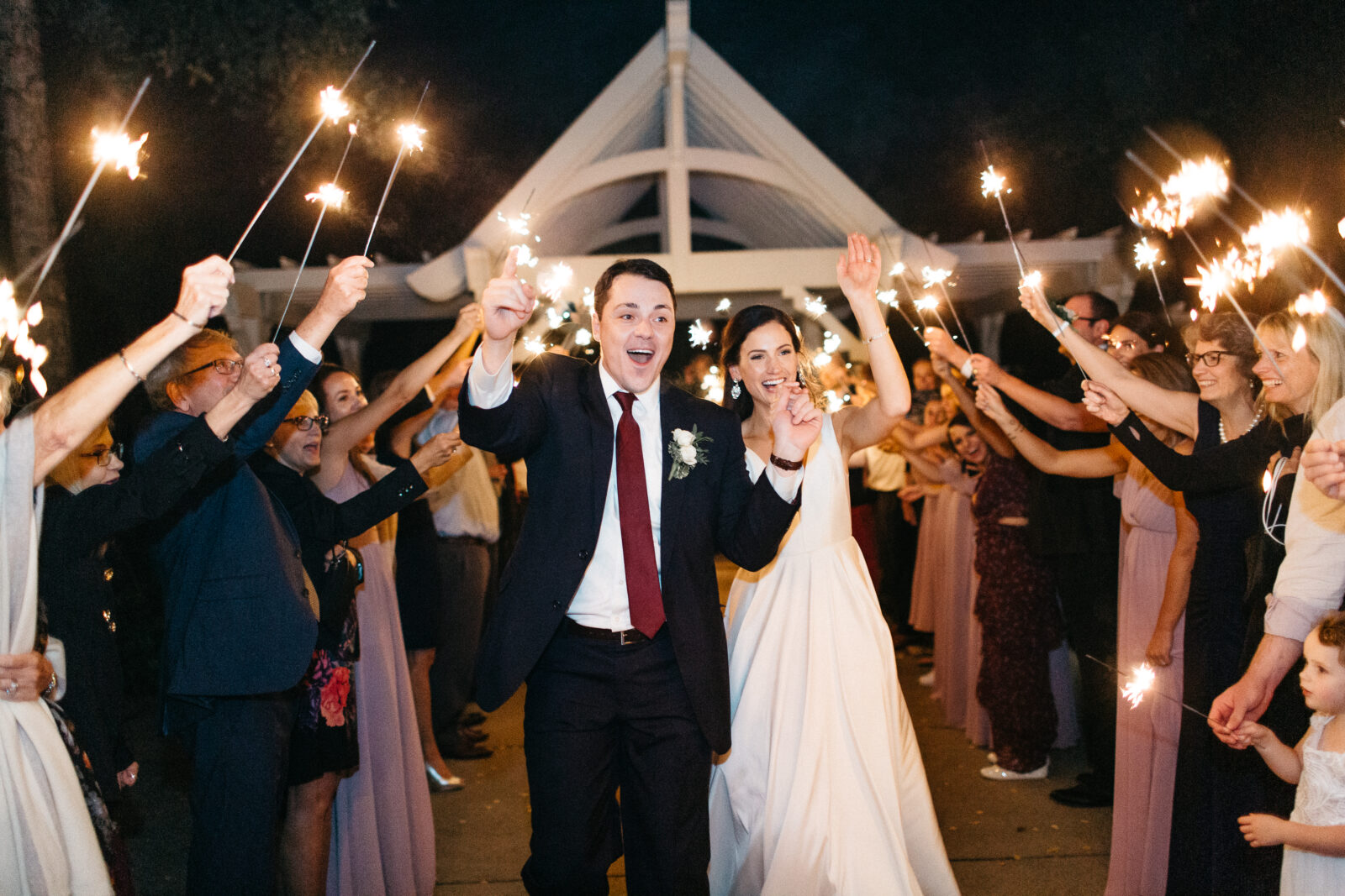 This photo shows the grand exit of the bride and groom at their wedding at Bearpath Golf and Country Club. The couple and their guests participated in a magical sparklers parade. This final touch added a sparkling and enchanting moment to their already perfect day, making it a night to remember.