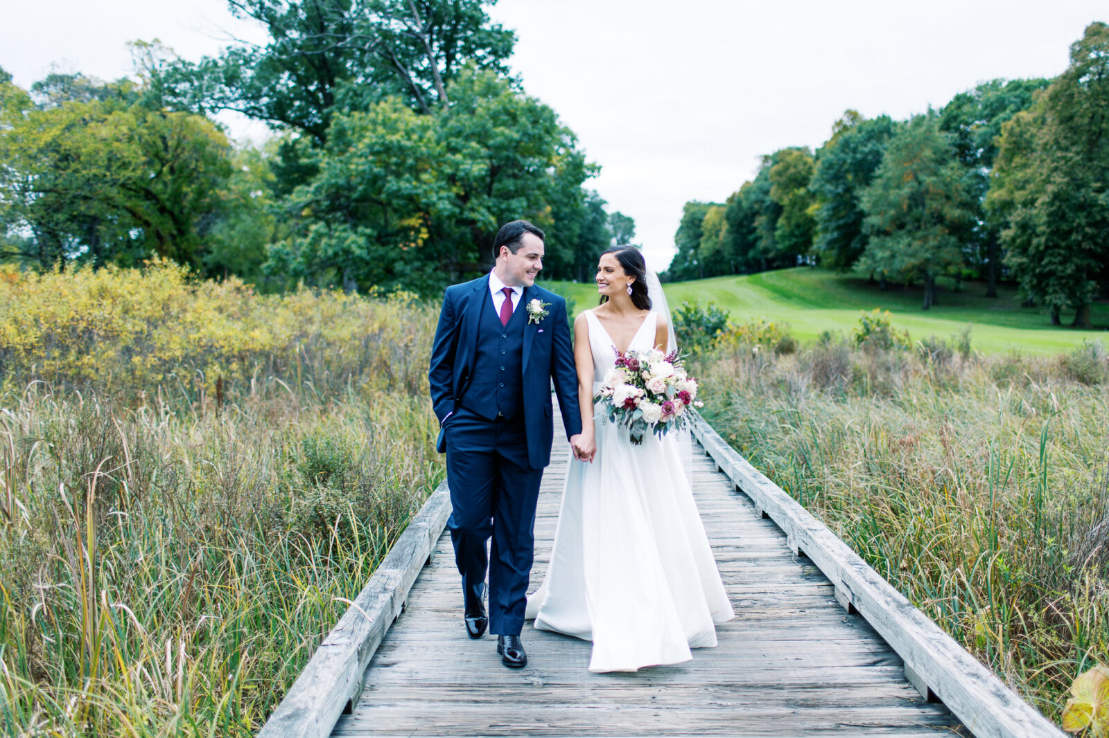 Bride and groom walking on the wooden walkway at Bearpath Golf and Country Club