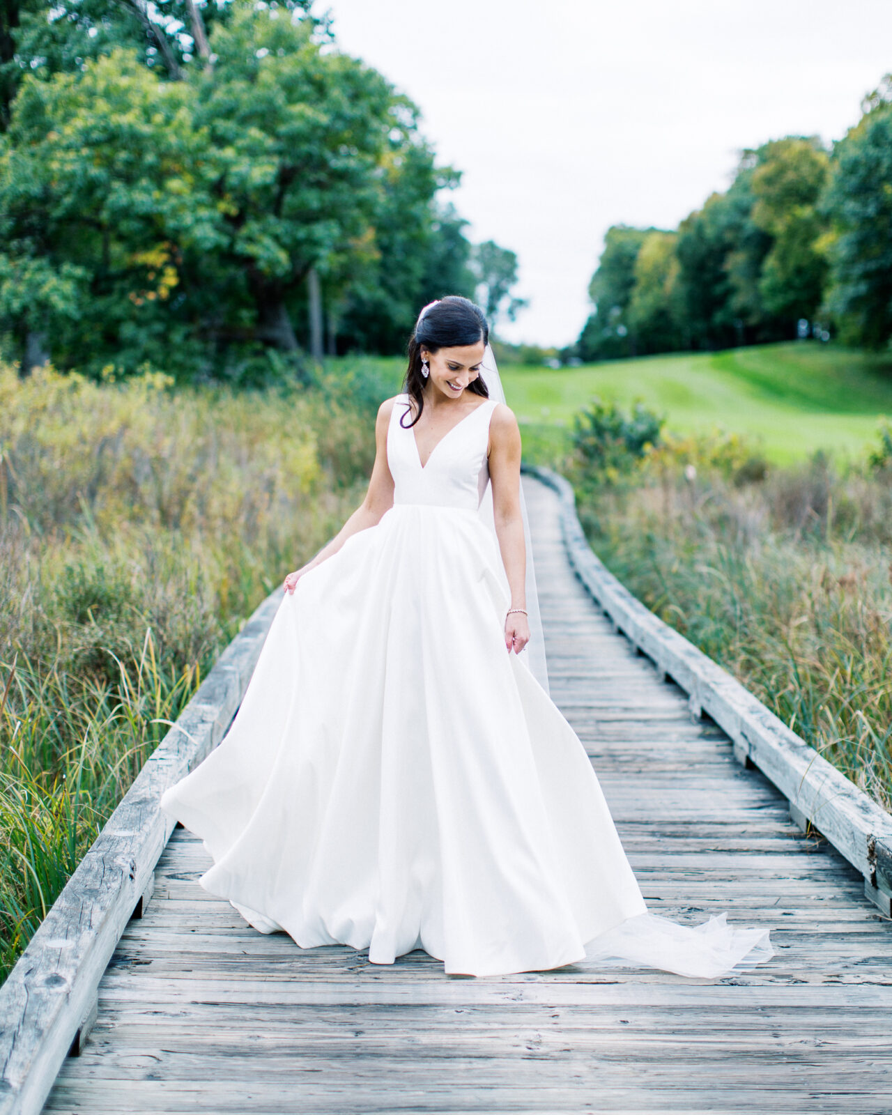 The bride is showing of her dress while Minnesota wedding photographer is capturing the moment