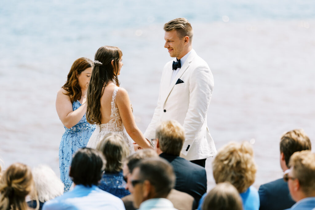 Photo of wedding at the Bluefin Bay Resort on the North Shore of Lake Superior, in Minnesota, where the groom is staring in awe at the bride as they do their ceremony. Picture was taken by Toly Dzyuba Photography.