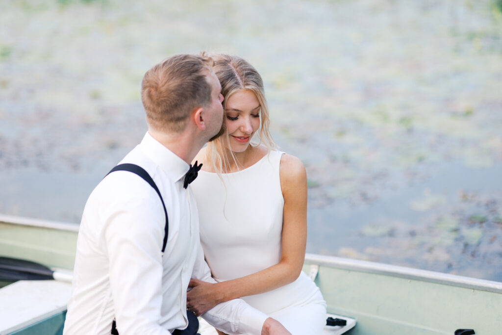 Groom kissing his bride in the boat on the lake of Detroit Lakes.