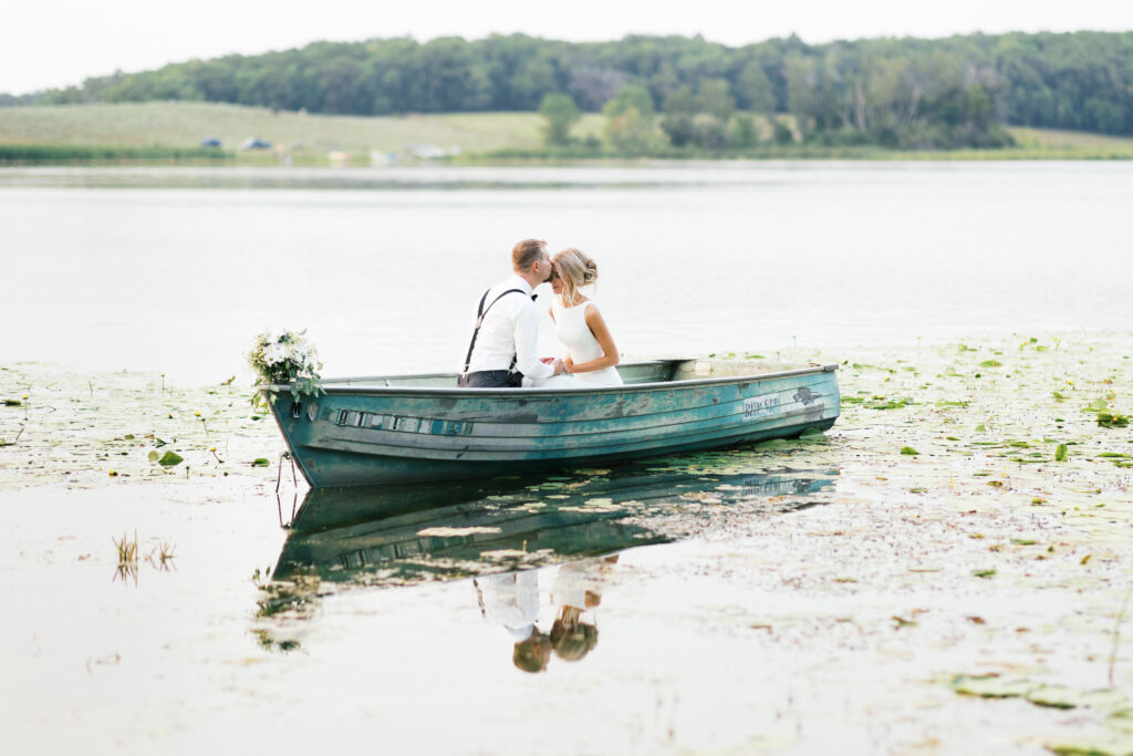 Groom kissing his bride's forehead in the boat on the lake. Minnesota wedding.