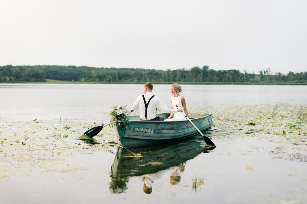 Bride and groom in the boat on the lake paddling. Detroit lakes wedding.