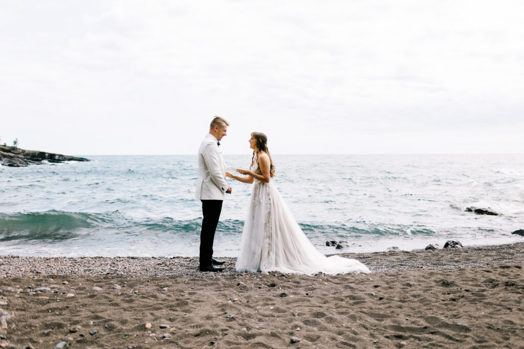 Bride and groom reading their vows on the North Shore, with Lake Superior in the background.