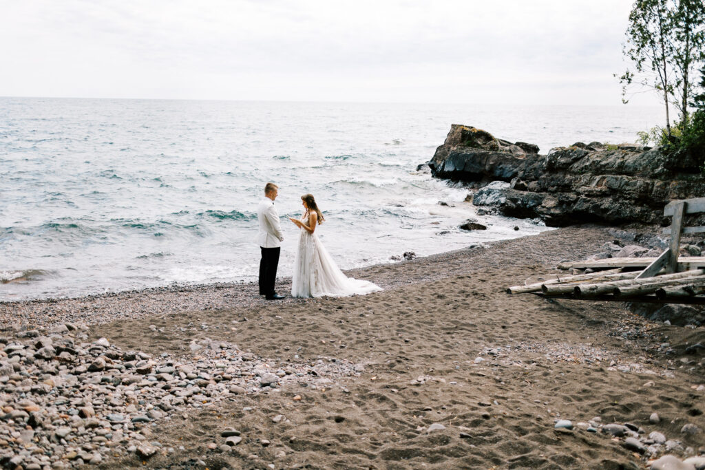 Bride and groom reading their vows on the North Shore, with Lake Superior in the background.