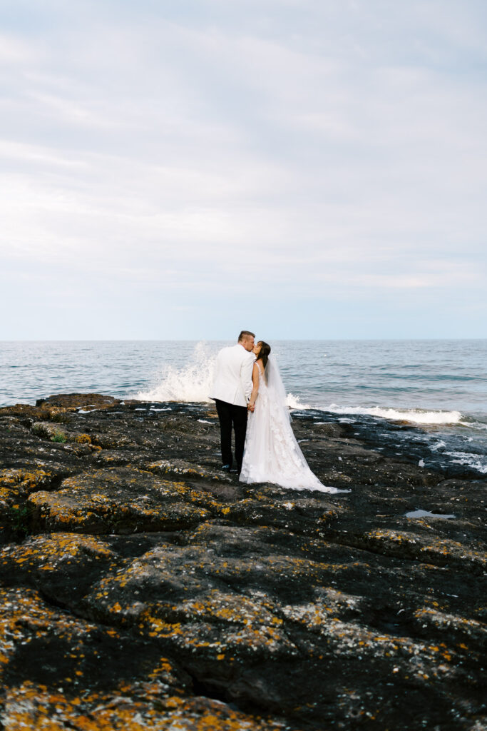 Waves splashing while newlyweds kiss on North Shore at Bluefin Bay Family Resort