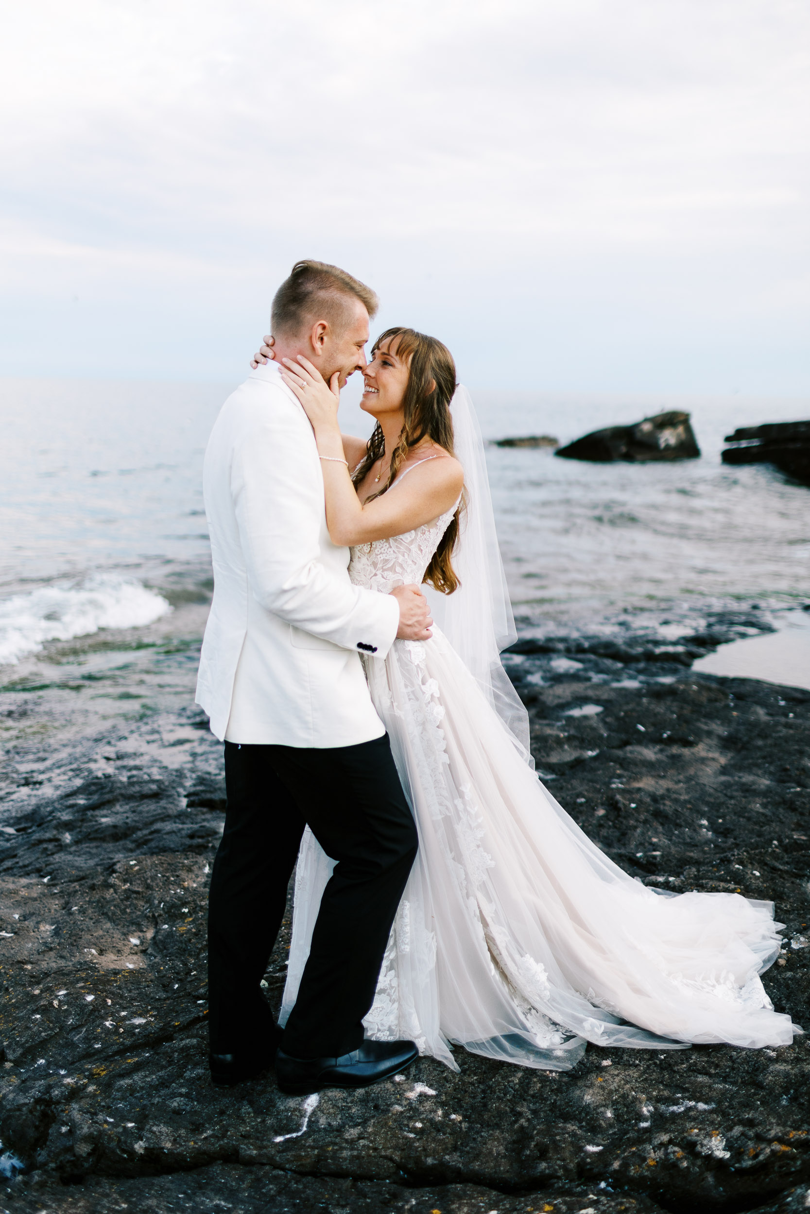 An intimate moment on Lake Superior at Bluefin Bay Resort. The bride and groom are sharing an embrace on a rocky outcrop. Photographer: Toly Dzyuba. Location: Bluefin Bay Resort, Minnesota's North Shore.