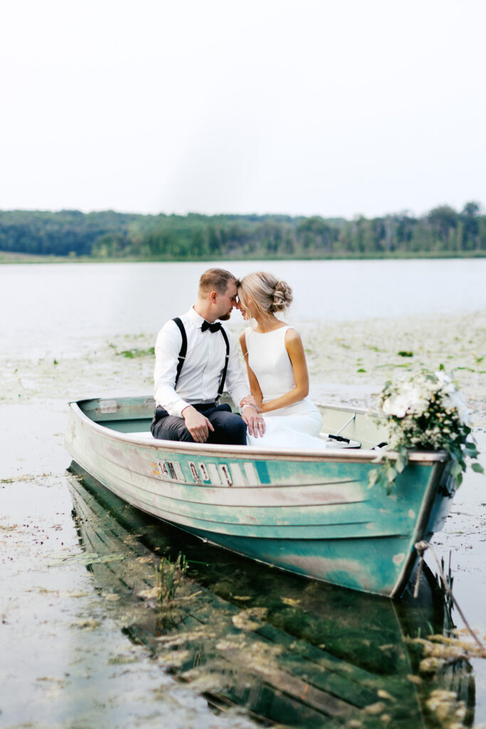 Newlyweds in the boat touching foreheads as they swim in the boat at Detroit Lakes