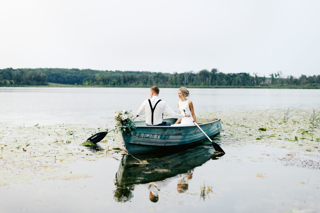 Newlyweds gliding in the boat across the water of the Detroit Lakes in Minnesota at golden hour.