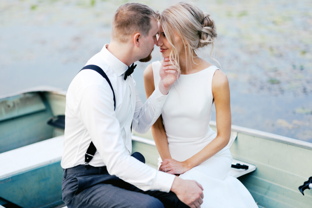 Bride and Groom touching foreheads in the boat at golden hour.