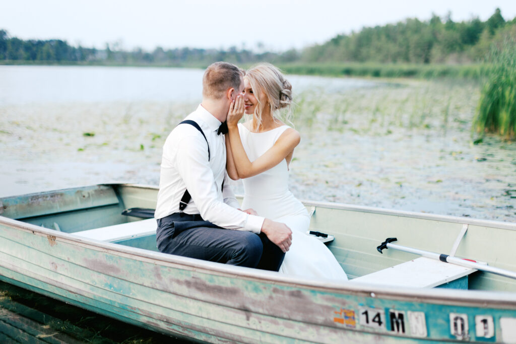 Minnesota wedding photographer photographers newlyweds in the boat smiling. By Toly Dzyuba Photography.