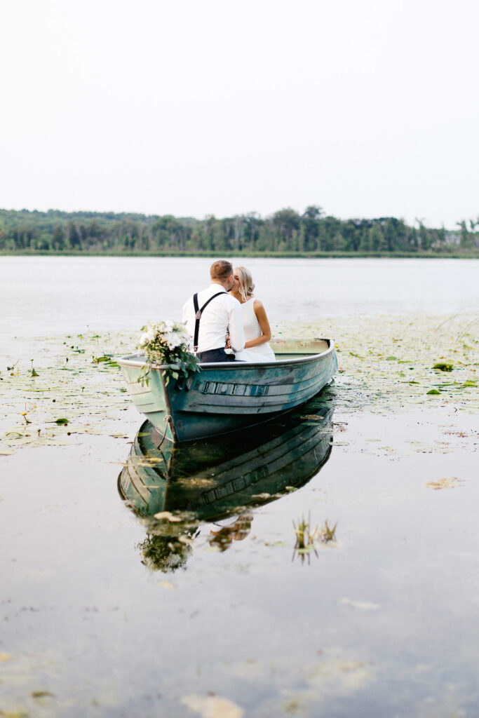 Newlyweds on the lake kissing while riding in the boat.