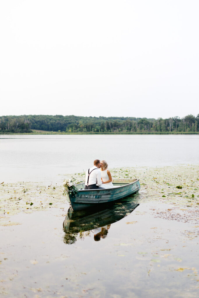 Newlyweds on the lake kissing while riding in the boat.