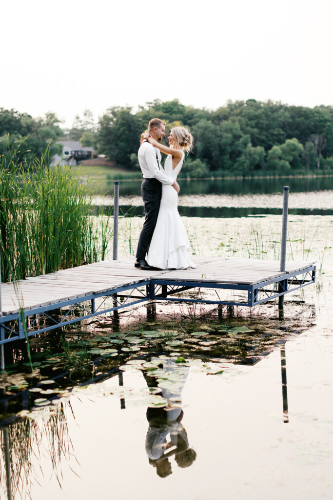 Bride and groom dancing on the dock with a sunset.