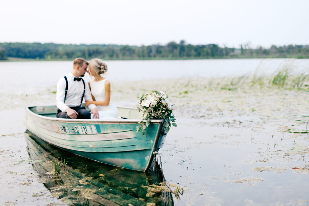 Minnesota wedding photographer captures bride and groom in the boat in the moment of Detroit Lakes by toly Dzyuba Photography