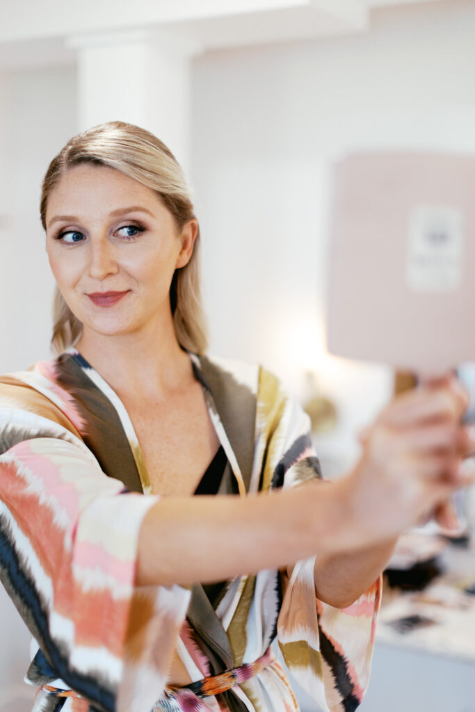 Bride is getting ready and looking at herself in the mirror at Ivory North