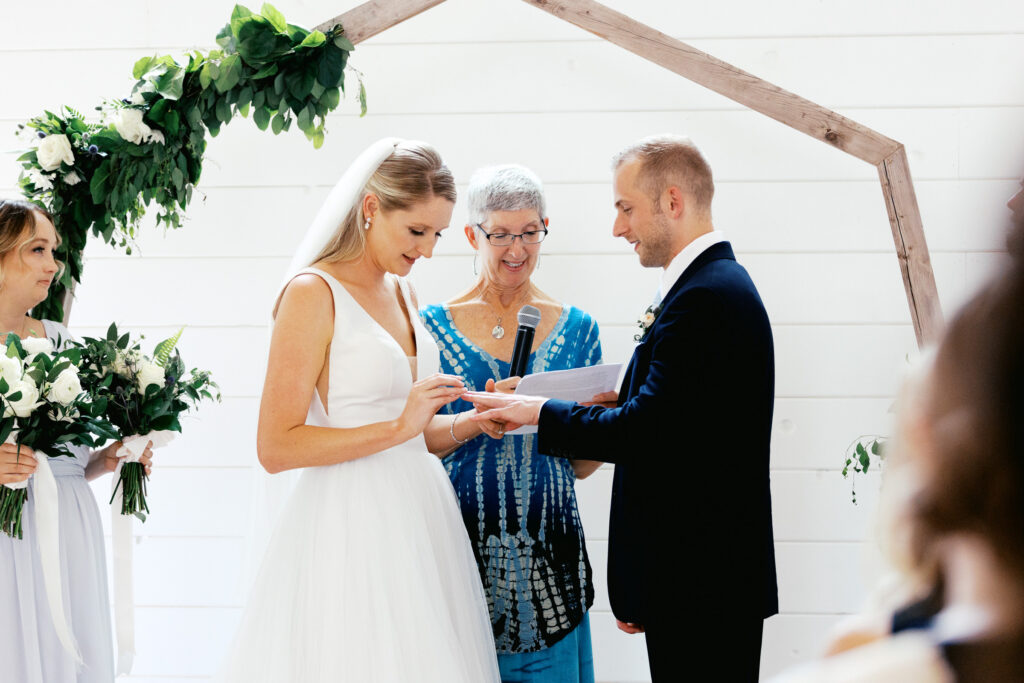 Bride is putting on the wedding ring on his finger at Ivory North