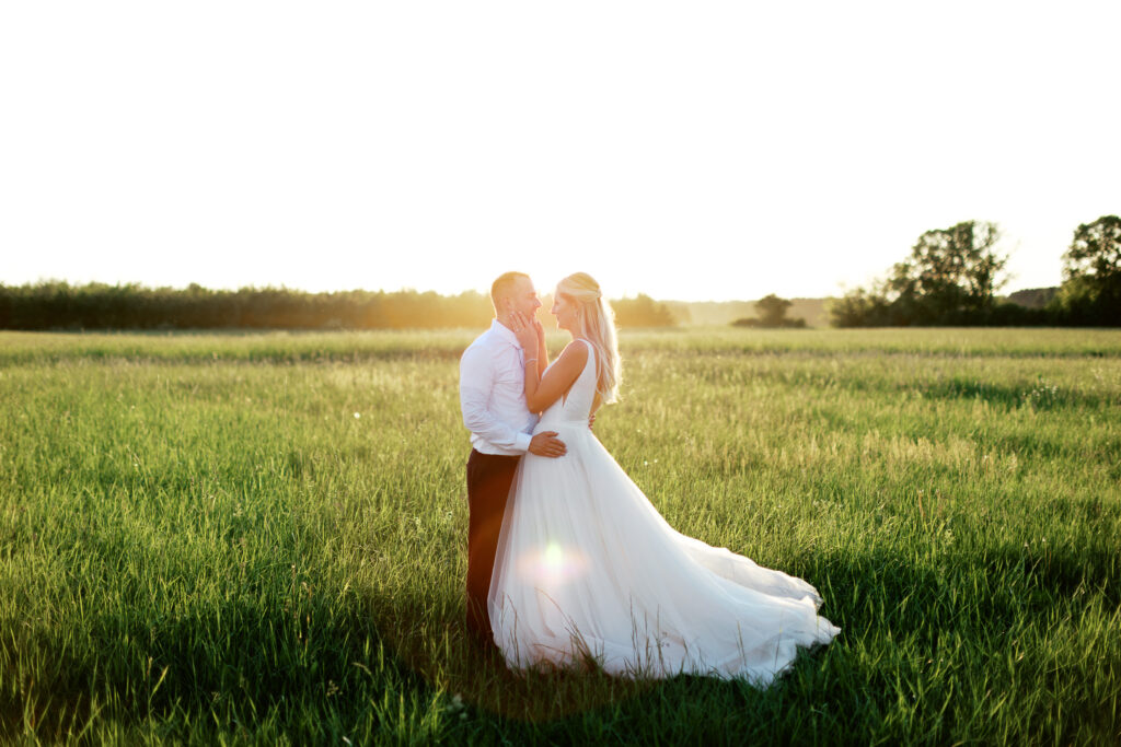 Newlyweds looking at each other's eyes with sunset glowing on the back. By Toly Dzyuba Photography.