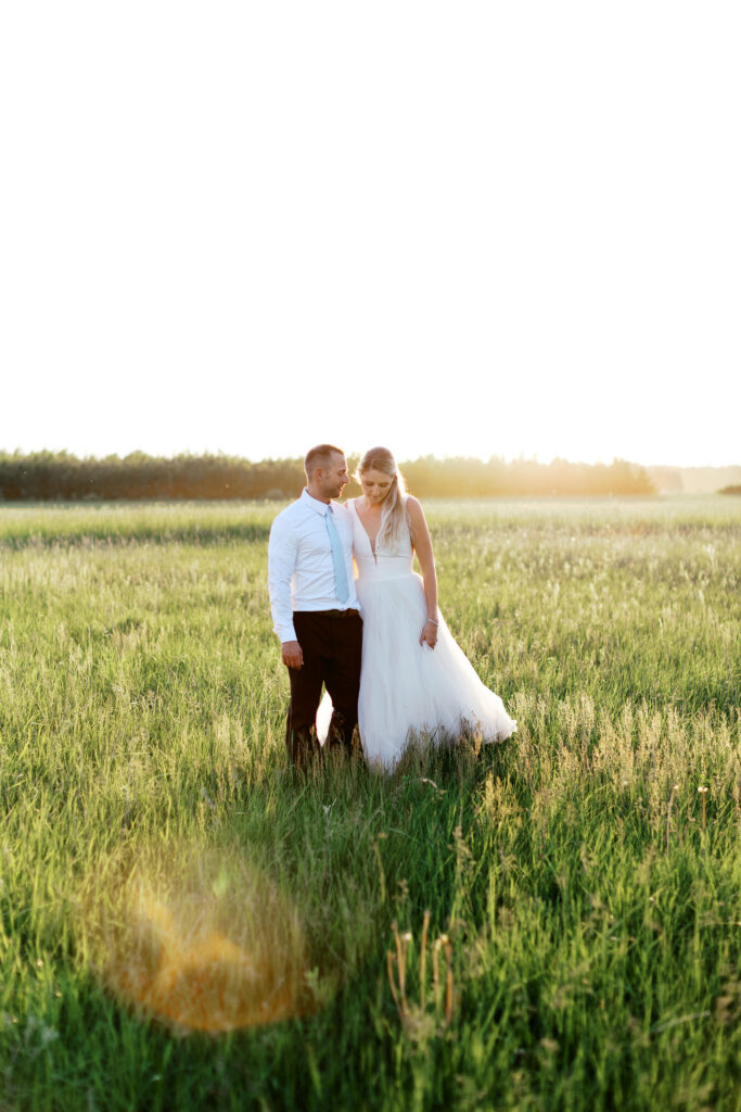 Bride and Groom on the field of Ivory North going for a stroll at sunset with stunning glowing light that surrounds them.