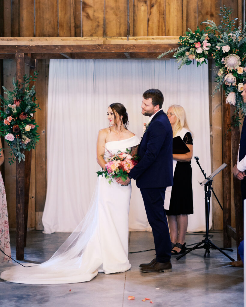 Bride and groom standing together holding hands during their wedding ceremony at Abella Weddings and Events in Minnesota, photographed by a Minnesota wedding photographer