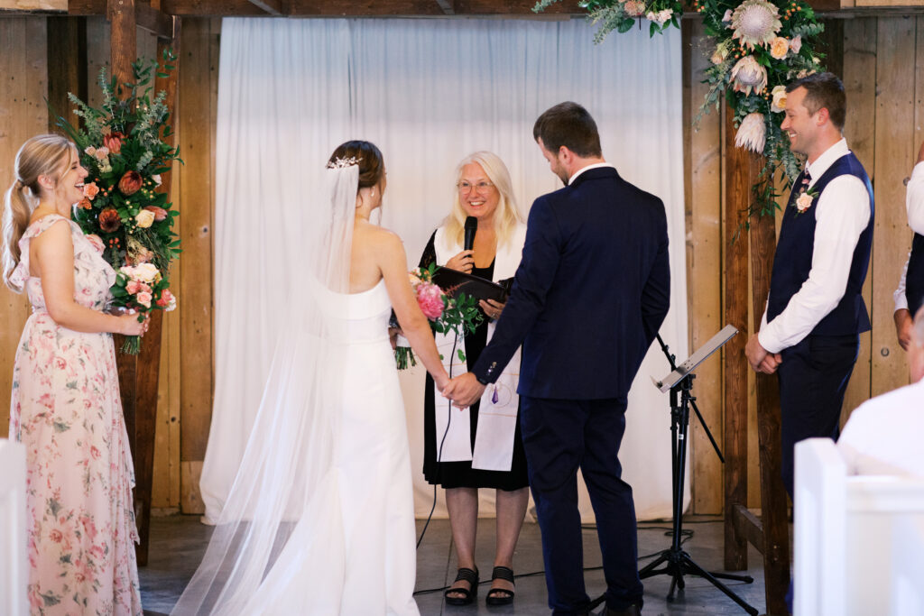 Bride and groom standing together holding hands during their wedding ceremony as they say their vows at Abella Weddings and Events in Minnesota, photographed by a Minnesota wedding photographer