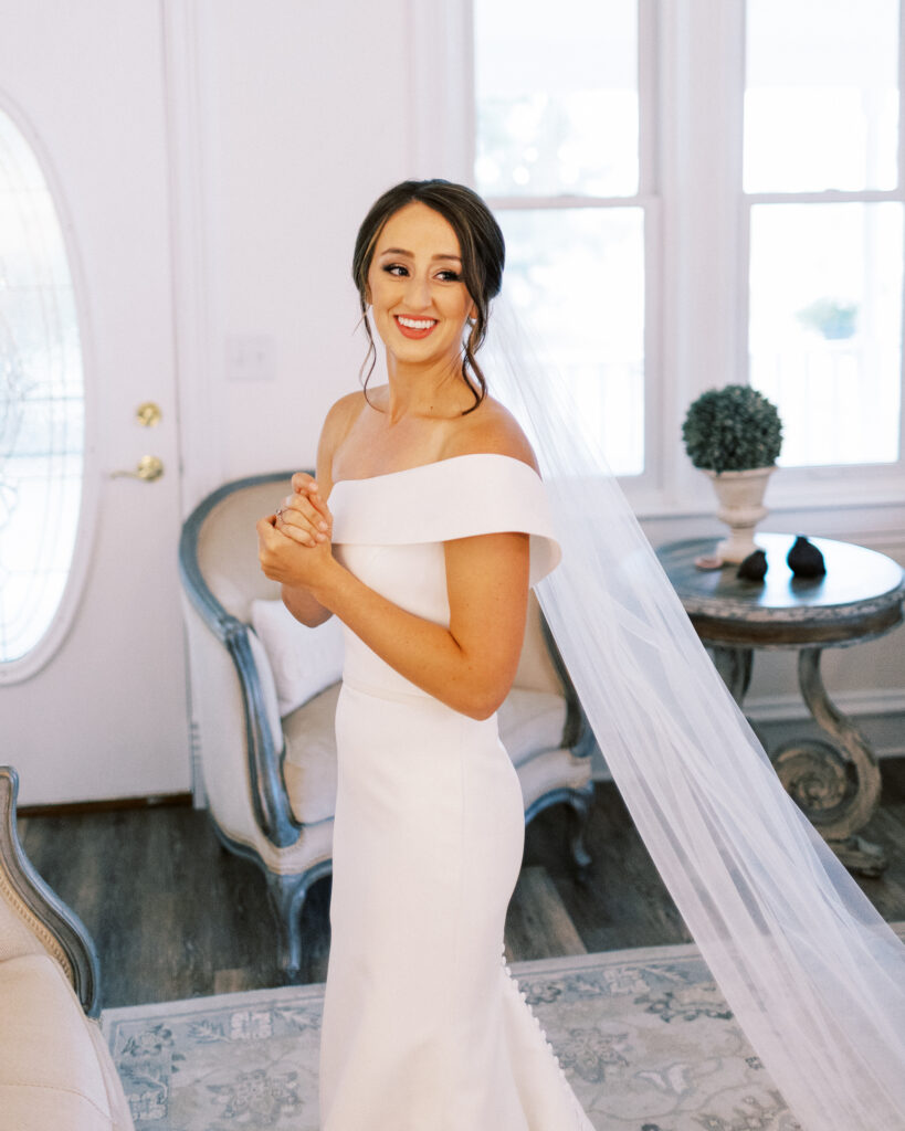 Bride in her dress getting ready with a smile at Abella Weddings and Events in Minnesota, captured by Minnesota wedding photographer.