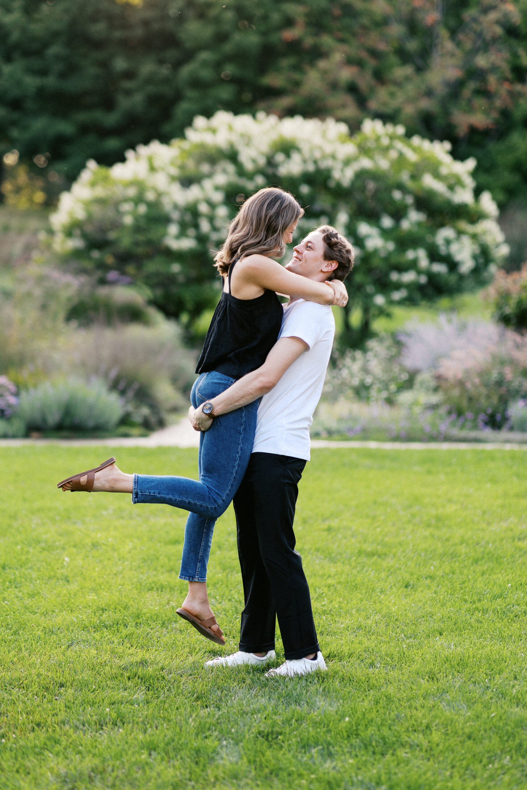 He picks her up with great joy in the gardens, with the sunset casting a golden glow around them. Captured by Toly Dzyuba Photography.