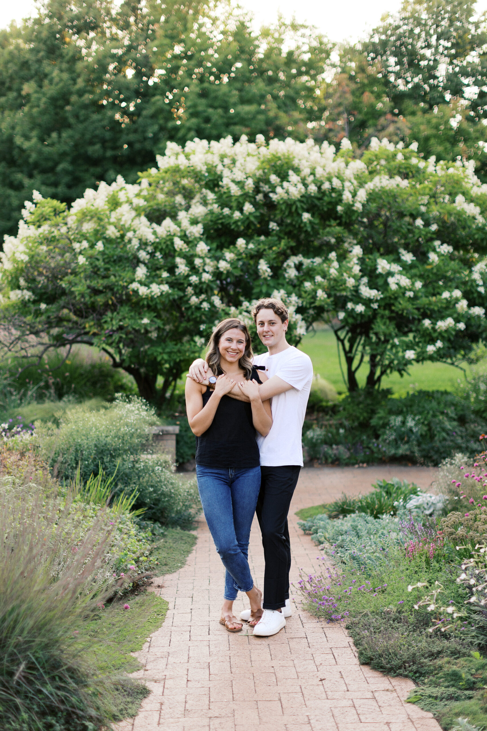 Couple is standing with arms wrapped and looking the the camera.