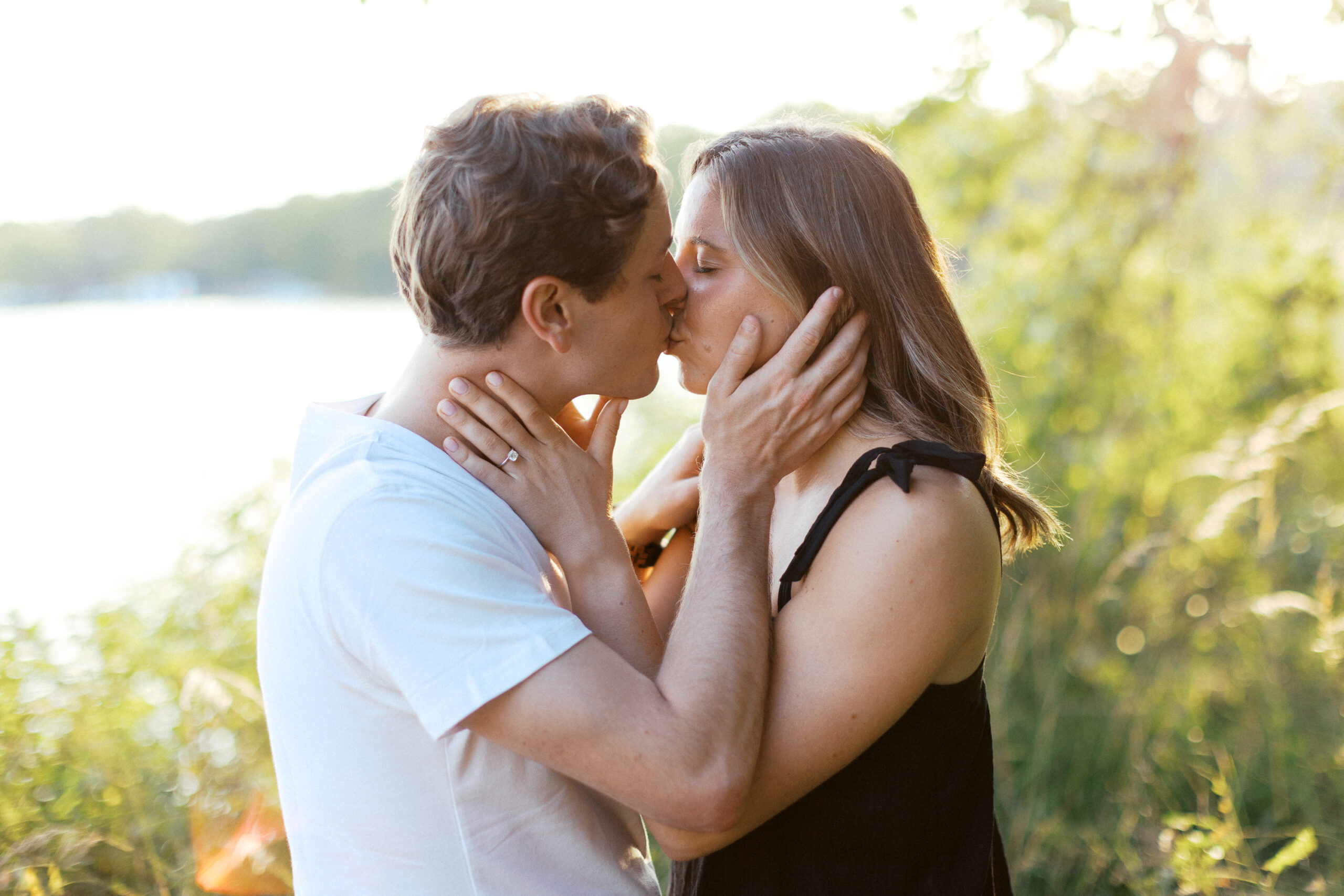 A tender moment as the couple holds each other's faces and shares a kiss, bathed in the warm glow of the sunset. Captured by Toly Dzyuba Photography.