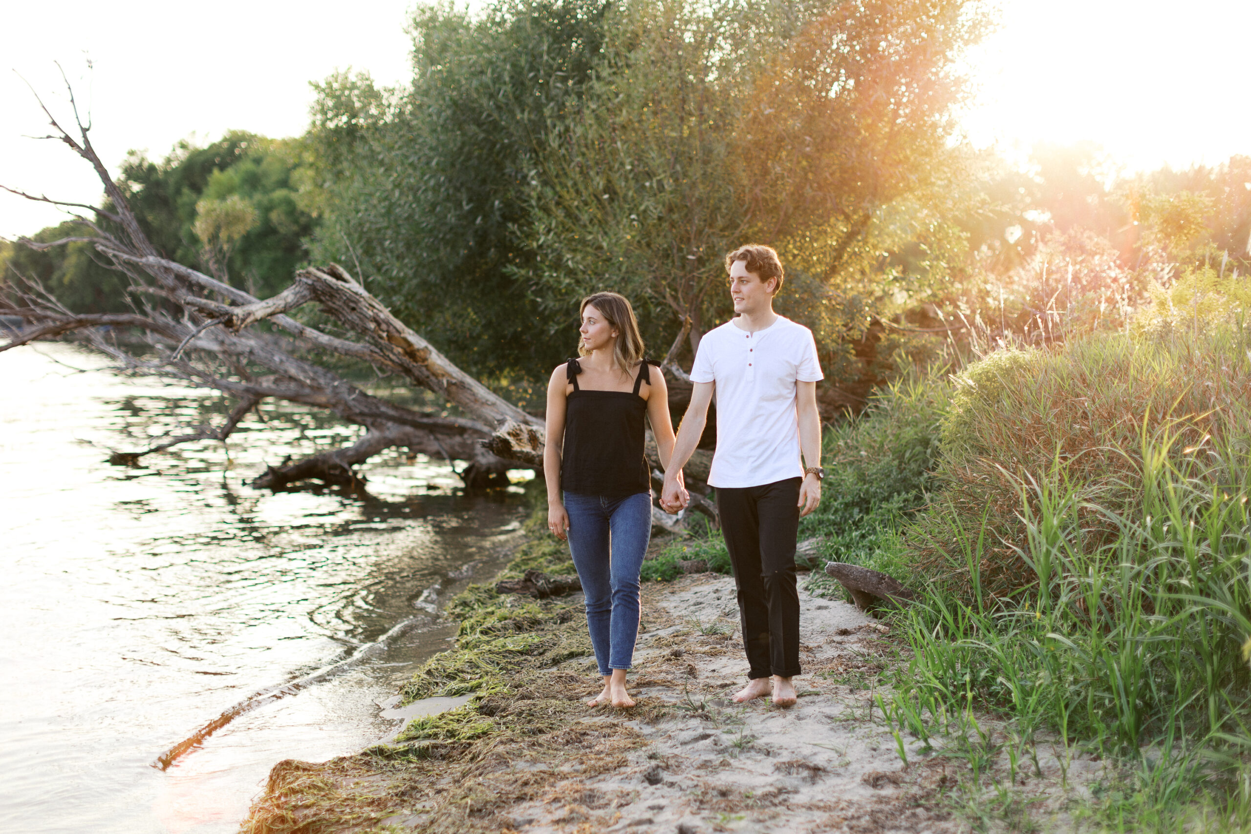 A beautiful moment as the couple walks hand in hand along the beach by Lake Minnetonka, looking out over the water. Captured by Toly Dzyuba Photography.