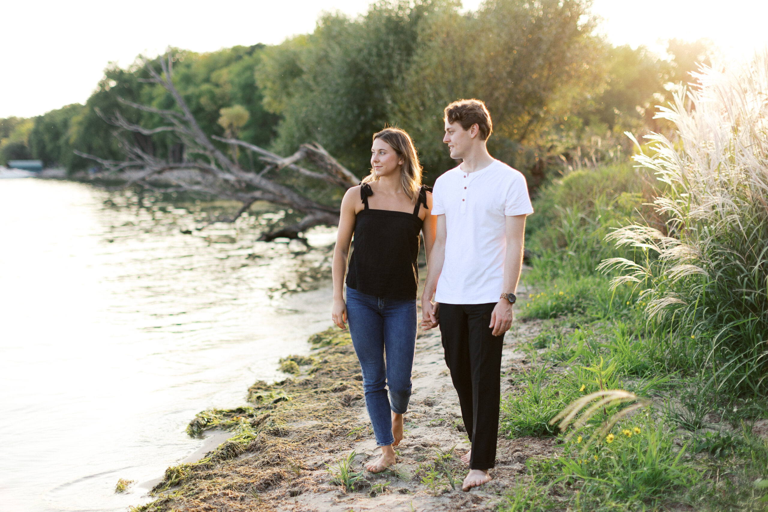 A peaceful moment as the couple walks barefoot along the beach, admiring the beauty of Lake Minnetonka. Captured by Toly Dzyuba Photography.