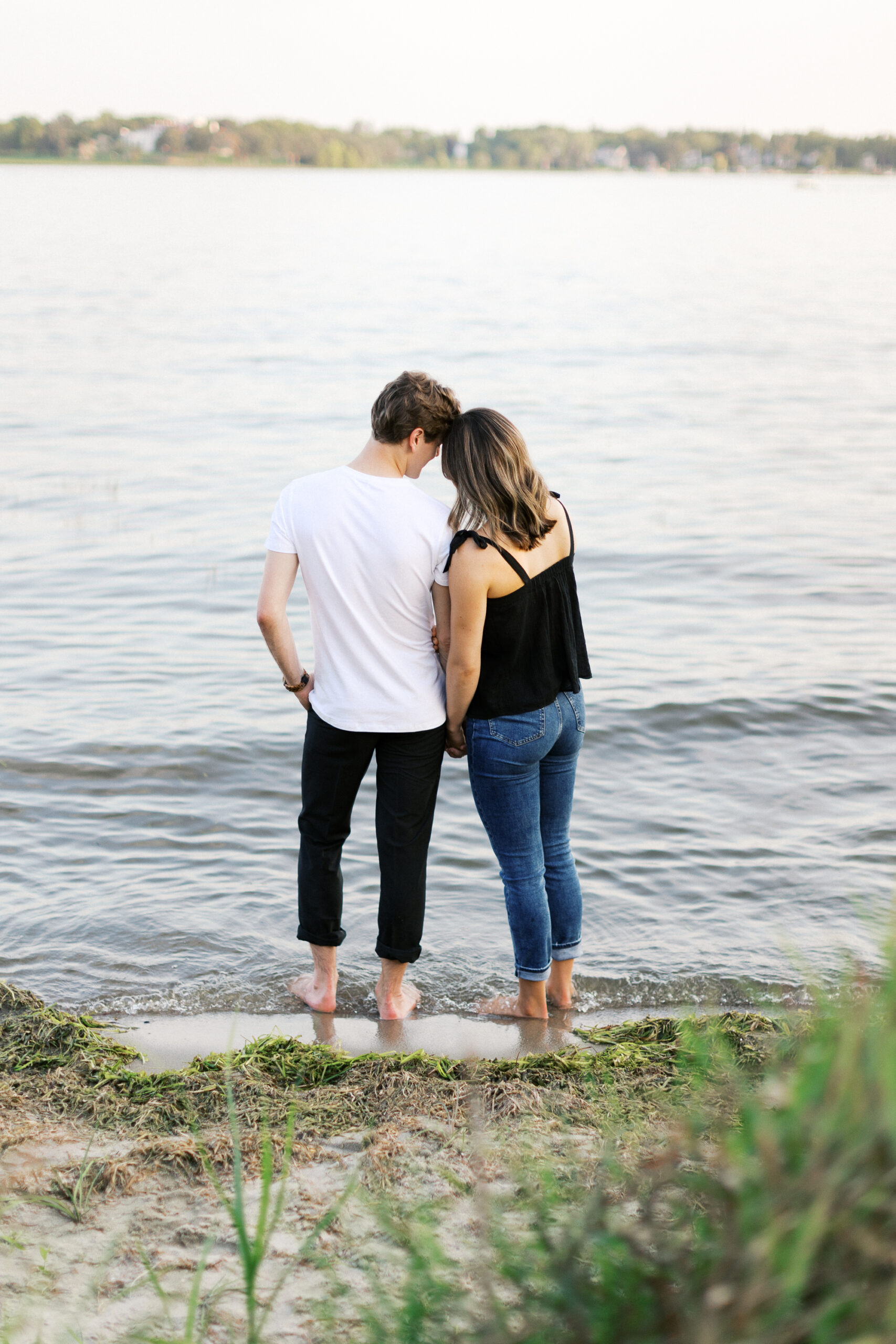 The couple stands barefoot in the lake, their love captured in a beautiful moment. Captured by Toly Dzyuba Photography.